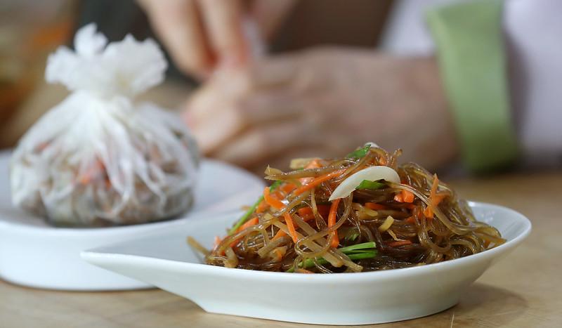 Es un plato coreano que consiste en fideos de celofán hechos con almidón de camote, salteados con vegetales y otros ingredientes, y típicamente sazonados con salsa de soja y aceite de sésamo. | Korea.net DB