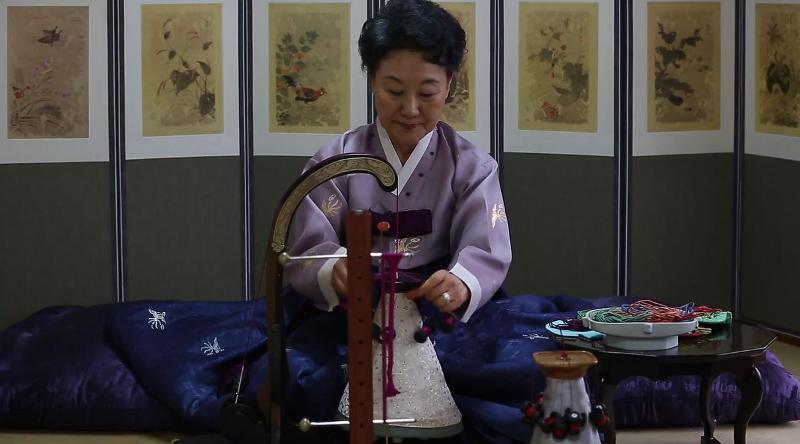 Kim Eun-young demuestra cómo hacer un nudo. | Captura de pantalla de Canall 'The Korea Times Photo Team' en YouTube.