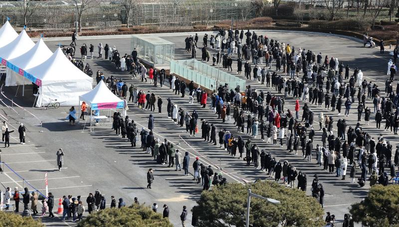 La tarde del 6 de febrero los ciudadanos hacen fila para realizarse la prueba de COVID-19 en la clínica de detección instalada en el estacionamiento del Complejo Deportivo de Jamsil, en el distrito de Songpa-gu en Seúl. A las 0 horas de ese día, el Gobierno anunció que el número acumulado de casos confirmados de COVID-19 había rebasado levemente el millón.