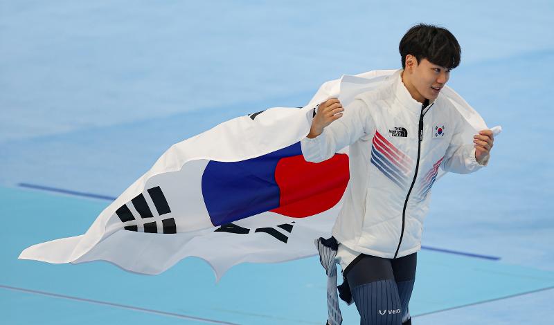 Kim Min-seok ondea la bandera nacional coreana el 8 de febrero en el &Oacute;valo Nacional de Patinaje de Velocidad de la capital china despu&eacute;s de hacerse con la medalla de bronce de los 1.500 metros masculinos en los Juegos Ol&iacute;mpicos de Invierno de Pek&iacute;n 2022. 