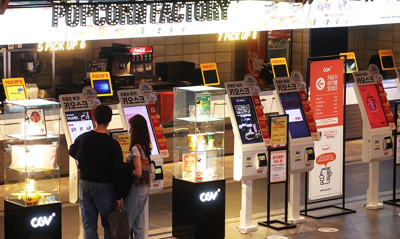 Según la Sede Central de Contramedidas de Seguridad y Desastres, a partir del 25 de abril, se permitirá comer y beber en instalaciones de usos múltiples bajo techo, como cines y supermercados. En la fotografía, unas personas compran palomitas de maíz y bebidas en un cine en Seúl el 24 de abril. 