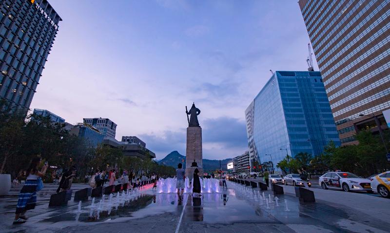 Los visitantes de la plaza Gwanghwamun en Seúl se paran alrededor de la fuente frente a la estatua del almirante Yi Sun-sin. 