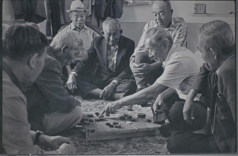 La foto, tomada el 1991, muestra a unos hombres mayores de Goryeoin juegan al janggi (ajedrez coreano) en Sandmak, un hogar para personas de edad en el pueblo de Kuilyuk en Tashkent, Uzbekistán. A diferencia del juego de cartas coreano hwatu (llamado Go-Stop), se dice que el janggi se está desapareciendo entre Goryeoin ya que la mayoría de las personas que lo juegan ya son mayores. | Museo Folclórico Nacional de Corea