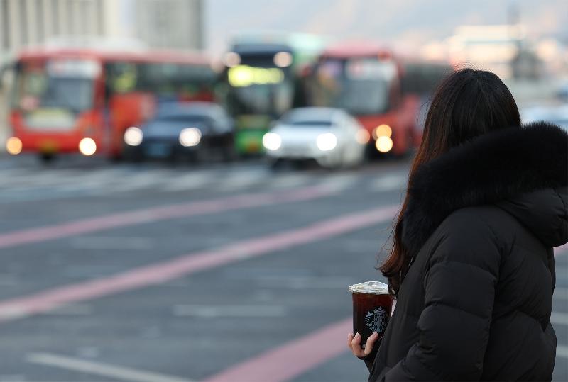 El 16 de febrero de 2022, una persona sostiene un café frío con hielos a pesar de la temperatura invernal de menos 11 grados centígrados mientras espera que cambie la señal en un cruce peatonal en el distrito Jongno-gu de Seúl. | Agencia de Noticias de Yonhap.