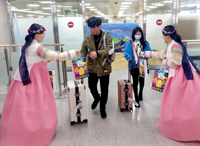 El 26 de marzo, unas trabajadoras del Aeropuerto Internacional de Jeju, entregan recuerdos a los turistas que llegan a la isla desde Shanghái, China.