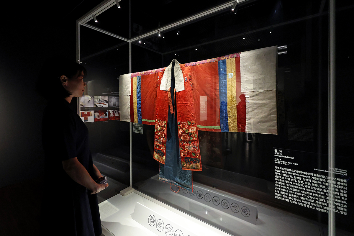 1En la mañana del 13 de septiembre, una trabajadora oficial observa un hwalot, el vestido de novia real usado en la dinastía Joseon, que hace parte de una de las piezas que se están presentando en la exposición especial 