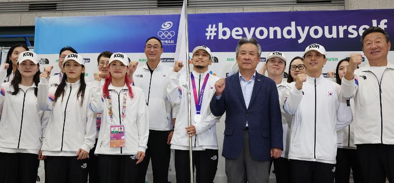 El 9 de octubre, una parte de la delegación de atletas surcoreanos se toma una fotografía con Lee Kee Heung (tercero desde la izquierda en la primera fila), el presidente del Comité Olímpico y Deportivo de Corea del Sur (KSOC, por sus siglas en inglés), en la Terminal 1 del Aeropuerto Internacional de Incheon. Ese día, Lee expresó su gratitud diciendo: “Toda Corea del Sur los animó y está feliz de ver que regresaron a casa sin sufrir ninguna lesión, aun después de haber logrado los resultados deseados