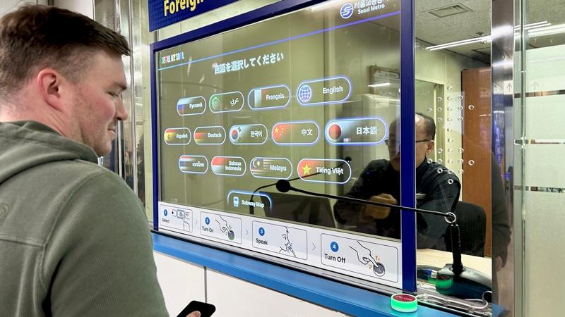 El 12 de diciembre, Eric Medema, un viajero de Michigan, Estados Unidos, utiliza el sistema de interpretación simultánea en idiomas extranjeros en la estación de Myeongdong. | Choi Jin-woo