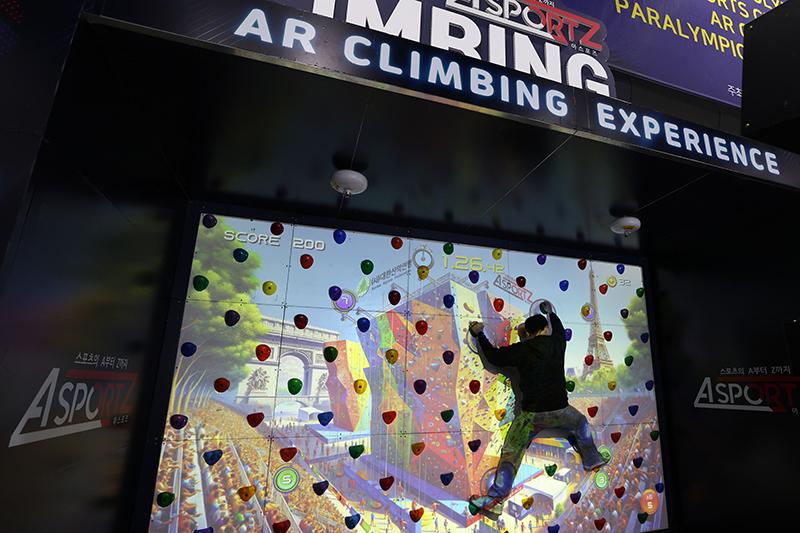 El 22 de febrero, una persona hace una demostración de escalada en roca con tecnología de realidad aumentada (RA) en el primer día de la Exposición Internacional de la Industria del Deporte y el Ocio de Seúl 2024, también conocido como SPOEX.