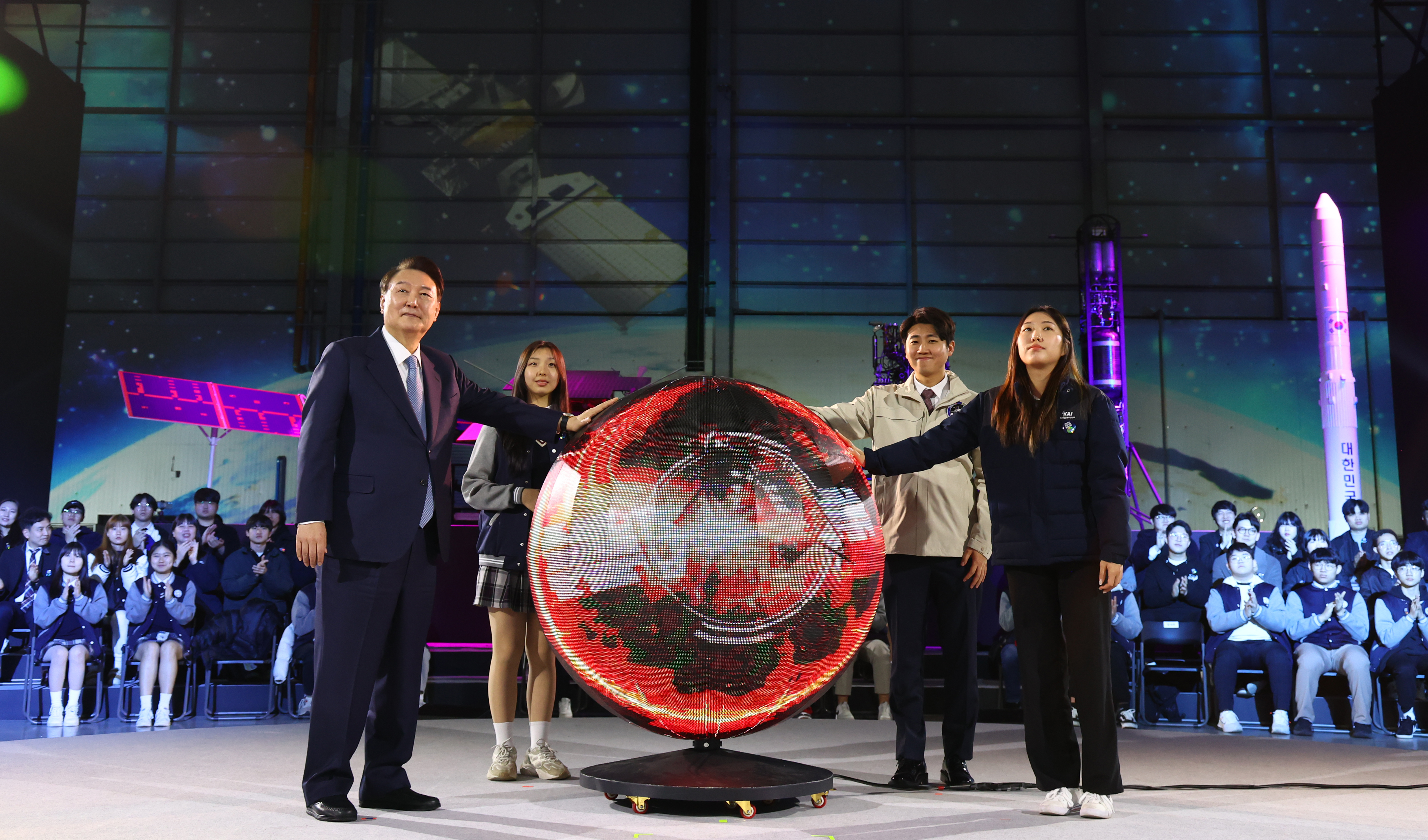 El 13 de marzo, el presidente Yoon coloca sus manos en un globo metálico como parte de una actuación en la ceremonia de lanzamiento de un nuevo clúster nacional para la industria espacial en Korea Aerospace Industries en la ciudad de Sacheon, provincia de Gyeongsangnam-do. En la ceremonia, Yoon prometió expandir el presupuesto de desarrollo espacial a más de 1,5 billones de wones para 2027. A finales de diciembre de 2022, el país lanzó su primer orbitador lunar, el Danuri, y realizó el tercer lanzamiento de su primer vehículo de lanzamiento desarrollado con la tecnología nacional el Nuri, el 25 de mayo de 2023. La Administración Aeroespacial de Corea se inaugurará el 27 de mayo de este año en la misma ciudad. 