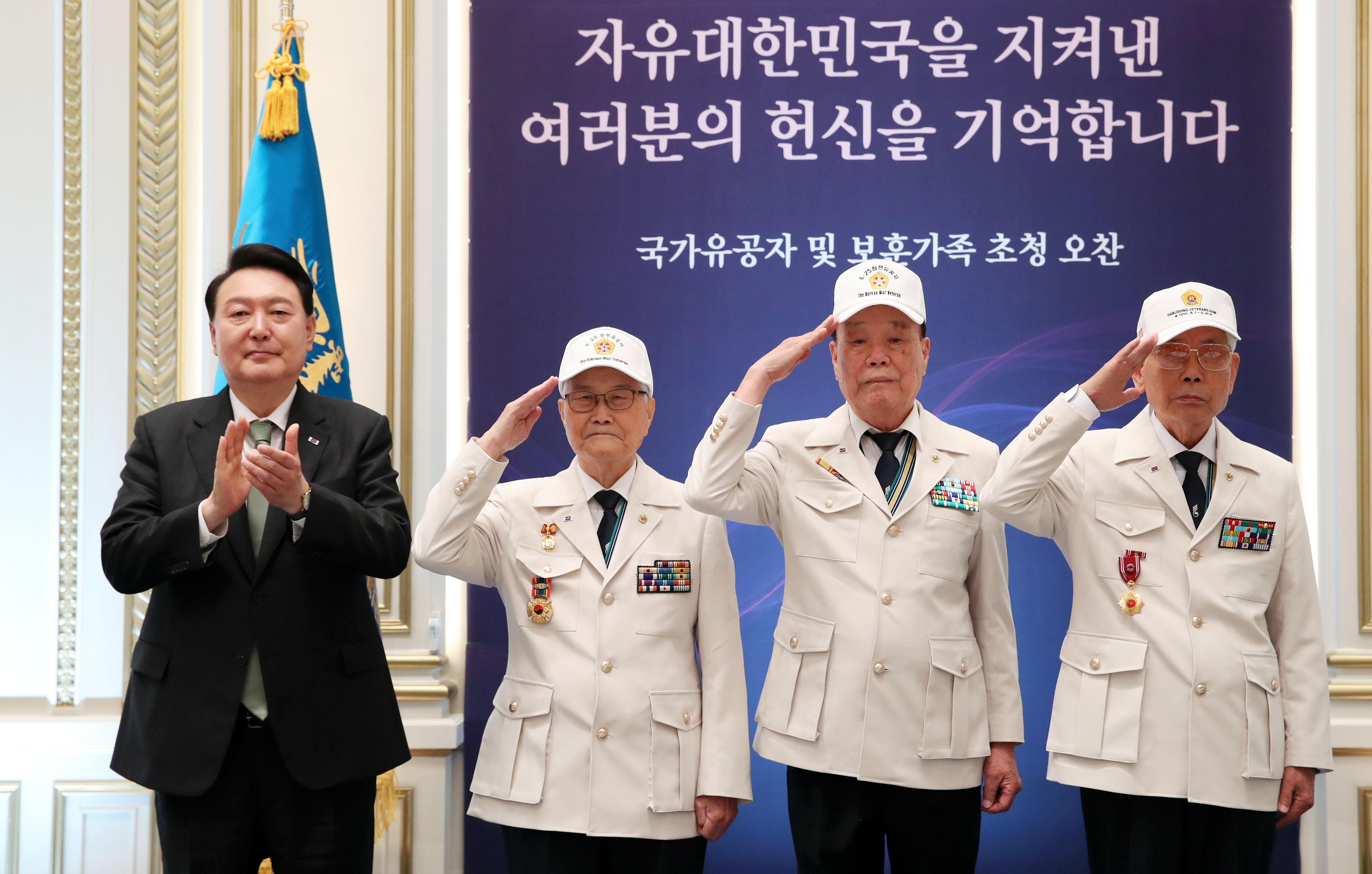 El 14 de junio de 2023, el presidente Yoon se toma una foto con Son Hee-won (2º desde la izda.), Kim Chang-seok y Lee Ha-young, directores de la Asociación de Veteranos de la Guerra de Corea a quienes vistió con 'uniformes de héroe', en un almuerzo para veteranos y sus familias en Yeongbingwan, la casa para visitas de Estado del antiguo complejo presidencial de Cheong Wa Dae. El Gobierno revisó la ley para que el Ministerio de Asuntos de Patriotas y Veteranos pasara de la categoría de 'subministerio' a 'ministerio de pleno derecho' el 5 de junio de 2023 y aumentó la compensación de los veteranos en un 5,5 por ciento ese año, el mayor aumento desde 2008.