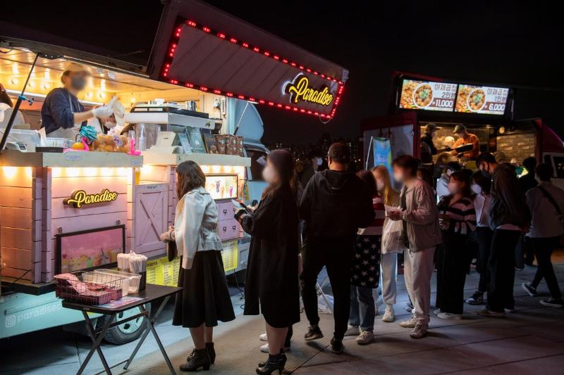 En junio de 2023, unas personas hacen cola frente a los camiones de comida en el Hangang Moon Light Market, celebrado en el Parque Banpo del río Hangang, en el distrito Seocho-gu de Seúl.