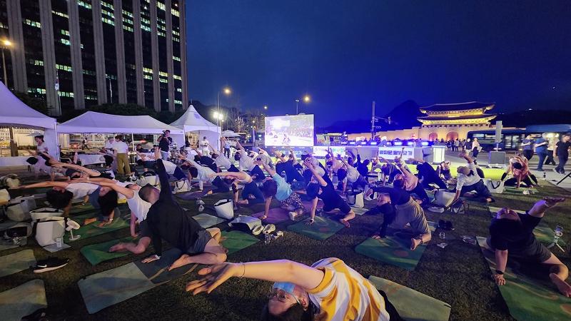 El 21 de junio, unas personas participan en el evento 'Gwanghwamun Moonlight Yoga', celebrado en Yukjo Madang de la plaza Gwanghwamun, en el distrito Jongno-gu de Seúl. | Lee Jihae