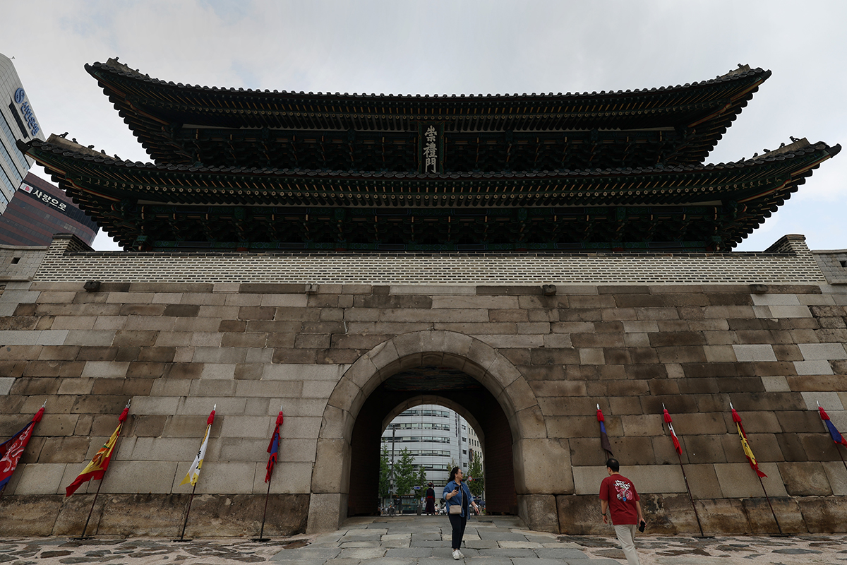 El 5 de julio, en medio de la temporada de lluvia, llamada jangma en coreano, unos ciudadanos caminan por la puerta de Sungnyemun, también conocida como Namdaemun, en el distrito de Jung-gu, Seúl. Durante la dinastía Joseon, cuando llegaba el jangma esta puerta permanecía abierta para equilibrar las energías del yin y el yang. Durante las sequías invernales, se hacía lo contrario.
