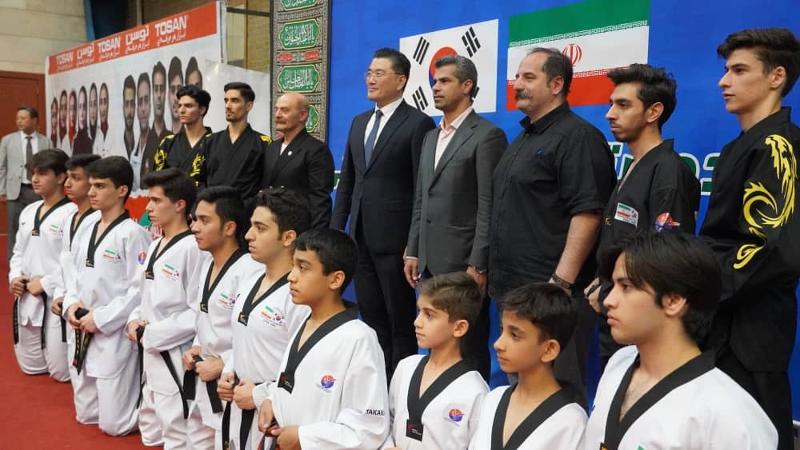 La foto muestra al embajador de la República de Corea en Irán, Kim Junpyo (cuarto desde la izquierda en la última fila) tomándose una foto con los atletas y funcionarios que participaron en la ceremonia de apertura del el 8º Torneo de Taekwondo de la Copa Embajador de la Amistad Corea-Irán, que se llevó a cabo el 8 de julio (hora local), en la Sala de conferencias de la Federación de Taekwondo de Irán, en Teherán. | Embajada de la República de Corea en Irán