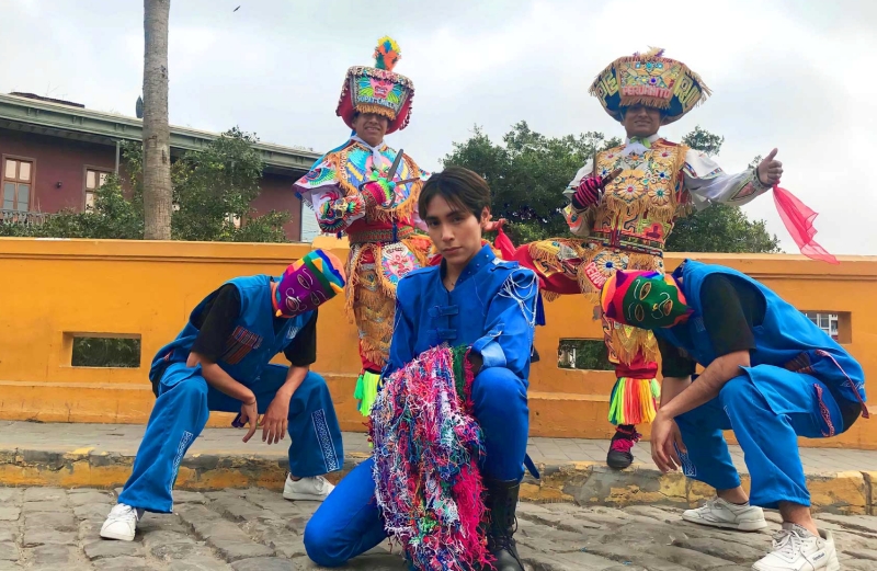 El pionero del Q-pop, Lenin Tamayo (centro), posa con bailarines vestidos con trajes y máscaras tradicionales peruanos.