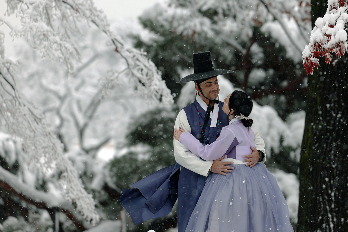 El 27 de noviembre, una pareja vestida con el traje tradicional coreano hanbok posa para una foto con la nieve de fondo en el palacio Gyeongbokgung, en el distrito Jongno-gu de Seúl.