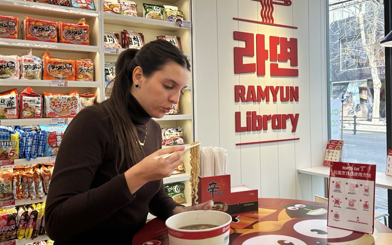 Una turista extranjera come fideos instantáneos en la tienda de conveniencia de la cadena CU 'Biblioteca de Ramyun', ubicada en el distrito de Mapo-gu, en Seúl. | Hong Angie