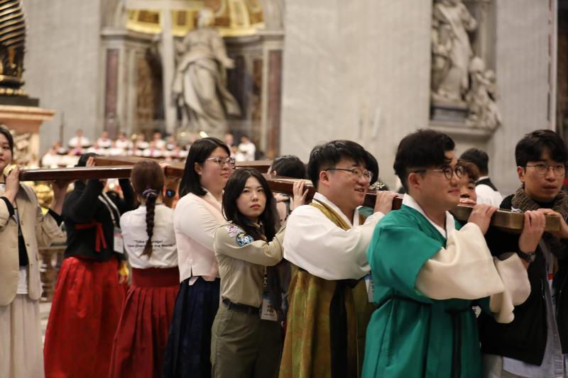 Algunos jóvenes coreanos reciben la cruz de madera, símbolo de la Jornada Mundial de la Juventud, de manos de jóvenes portugueses en la Basílica de San Pedro, en el Vaticano, el 24 de noviembre.