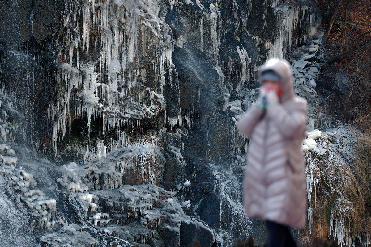 Una persona camina frente a una cascada artificial congelada, en el arroyo Hongjecheon, en el distrito capitalino de Seodaemun-gu, el 9 de enero, cuando se emitió la primera advertencia por ola de frío de la temporada invernal para toda la ciudad de Seúl. 