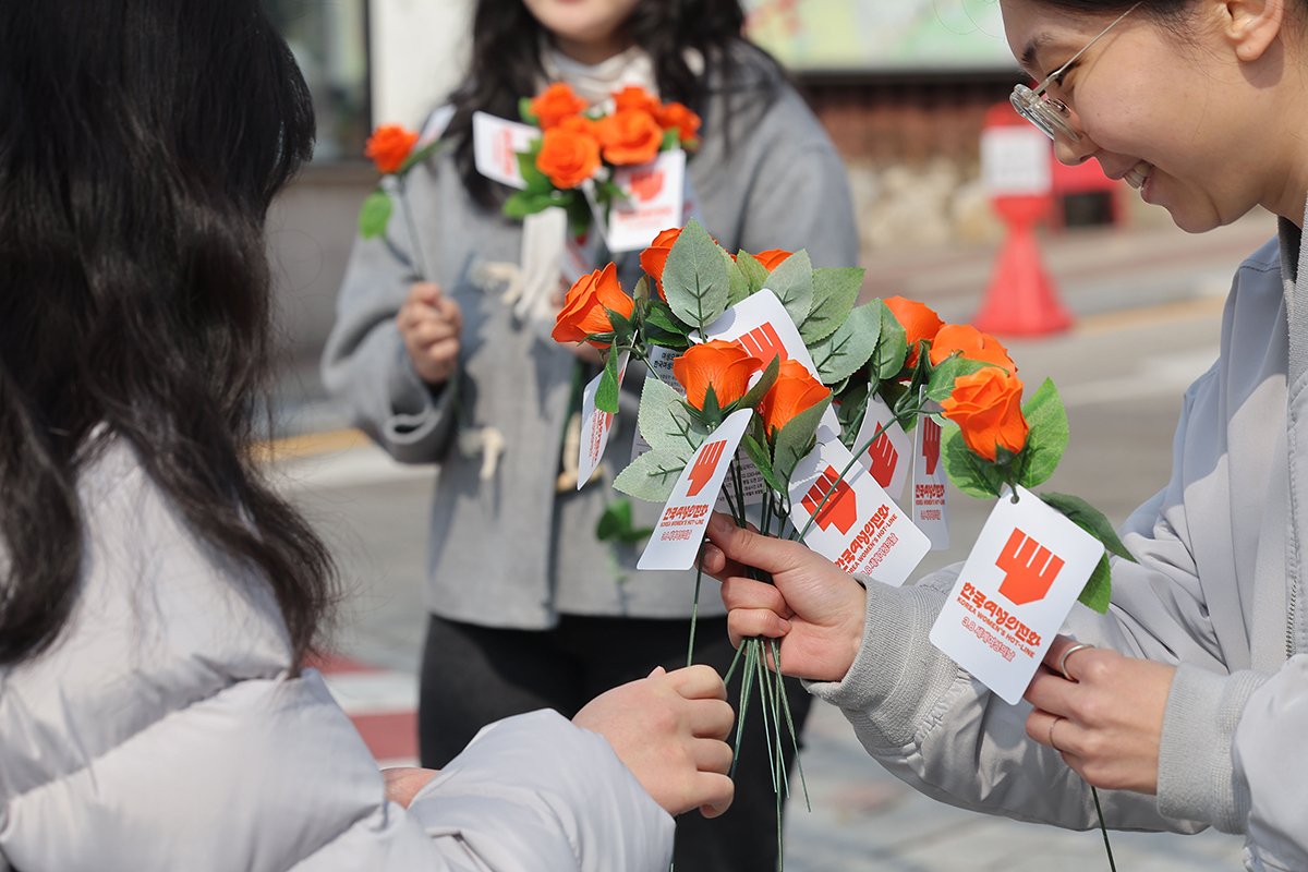 El 7 de marzo, un día antes del Día Internacional de la Mujer, unas empleadas de la Línea de Asistencia para Mujeres de Corea reparten rosas frente a una universidad femenina en Seúl.