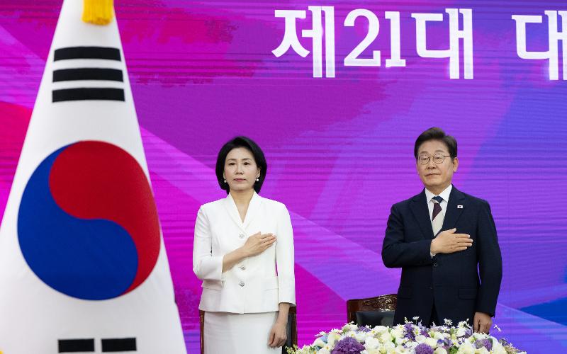 Lee (derecha) y su esposa Kim Hye-kyeong saludan a la bandera nacional durante la ceremonia de investidura en la Asamblea Nacional.
