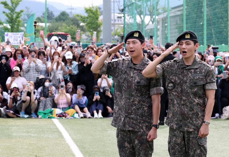 RM (izda.) y V, del grupo de K-pop BTS, saludan a sus fanes en un campo de fútbol en Chuncheon, en la provincia de Gangwon-do, el 10 de junio, tras ser licenciados del servicio militar obligatorio. | Agencia de Noticias Yonhap  