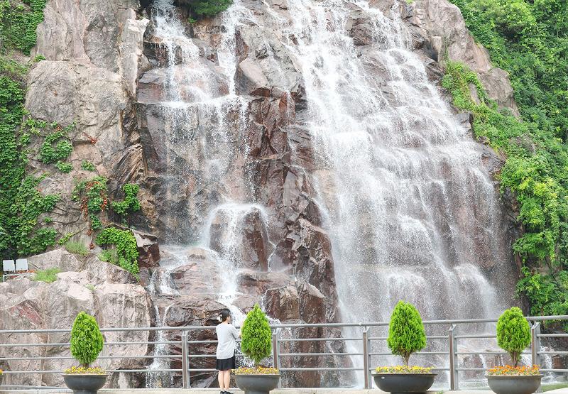 El 7 de julio, día de Soseo, uno de los 24 términos solares tradicionales del calendario lunar coreano que marca el inicio del calor sofocante del verano, una visitante se refresca mientras observa el agua en el parque de la Cascada Yongma, en el distrito de Jungnang-gu de Seúl.'