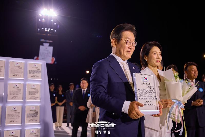 El presidente Lee Jae Myung, junto con la primera dama Kim Hea Kyung, posa ante la cámara luego de recibir 80 cartas de nombramiento, de parte de diferentes ciudadanos, durante una ceremonia especial llevada a cabo, el 15 de agosto, en la plaza Gwanghwamun, en el centro de Seúl. | Oficina presidencial