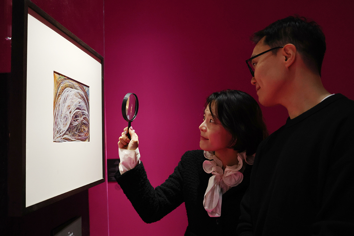 Una visitante observa una obra con una lupa durante la exposición “Seance: Technology of the Spirit”, parte de la Bienal Mediacity de Seúl, el 12 de noviembre, en el Museo de Arte de Seúl, ubicado en el distrito capitalino de Jung-gu.