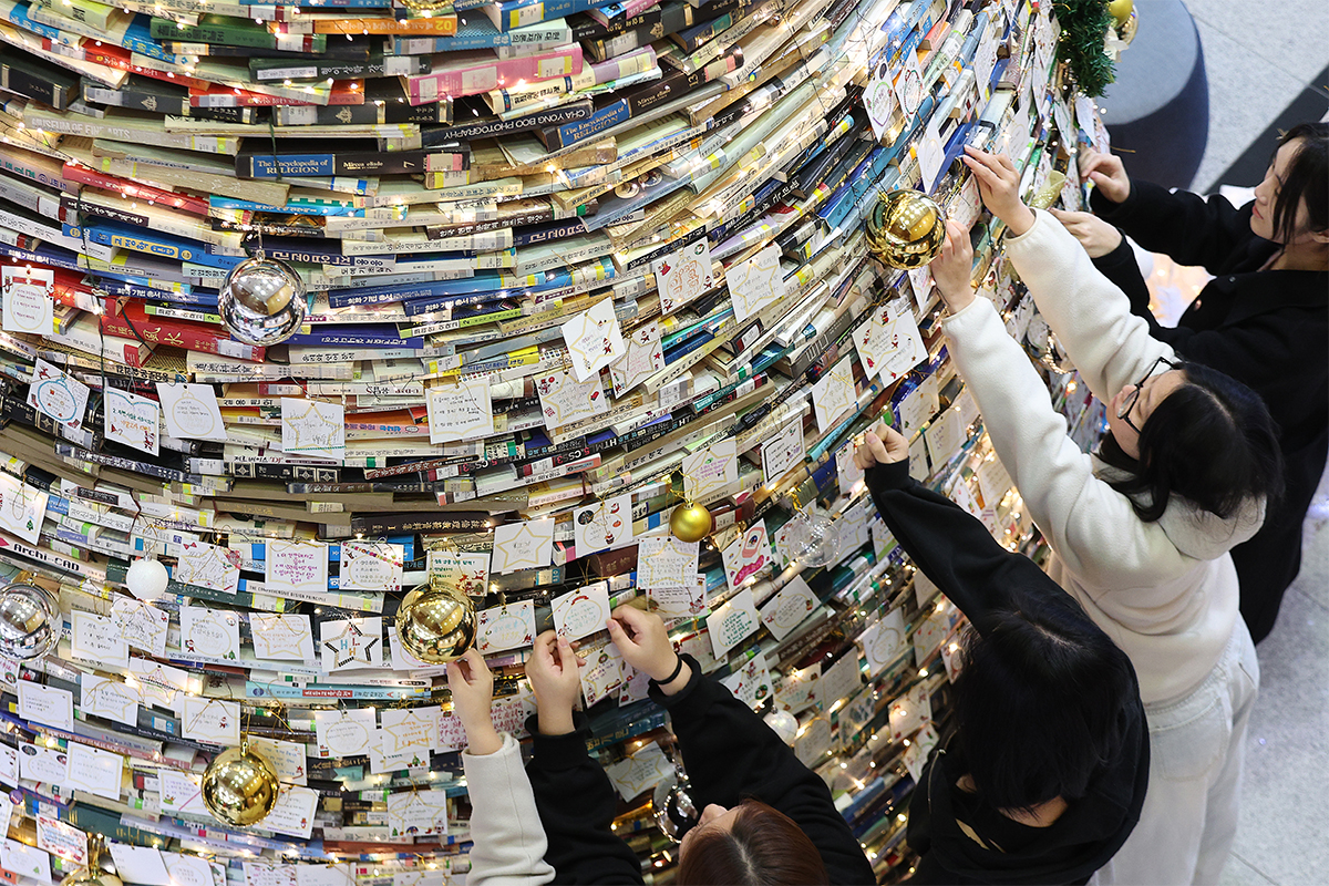 Unas estudiantes colocan tarjetas con deseos en un &aacute;rbol de libros instalado con motivo de la Navidad el 16 de diciembre en la biblioteca de la Universidad de Daegu.