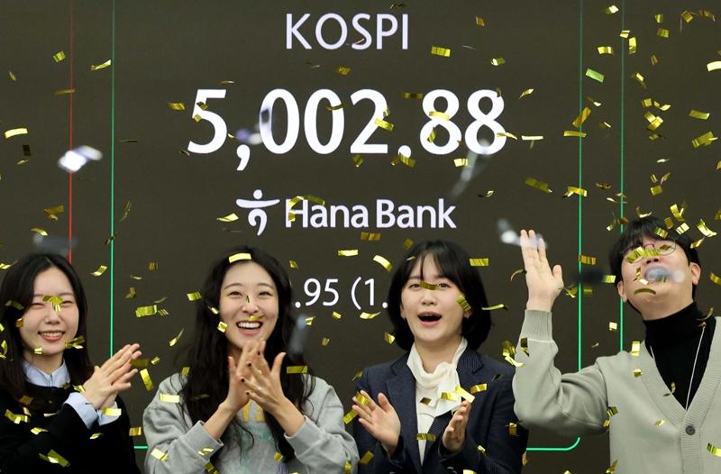 Los empleados del banco Hana Bank celebran después de que el Índice Compuesto de Precio Bursátil de Corea del Sur (KOSPI, por sus siglas en inglés) superara el nivel de 5.000 puntos, por primera vez en la historia, el 22 de enero, en la sala de operaciones del banco, en Seúl. | Agencia de Noticias Yonhap 