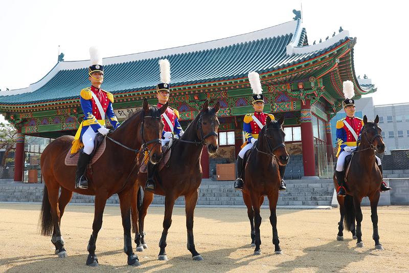 La foto muestra a cuatro cadetes montados sobre sus caballos en el Campo de Hwarang de la KMA. De izquierda a derecha: Kim gwanhong, Jang won hyeok, Yeon hyorin y Her junseok. Lo que antaño fuera una fuerza de caballería en el campo de batalla, hoy se preserva como una tradición simbólica que hereda el espíritu de la Academia. Aunque su función en combate ha cesado, el orden y la gallardía que la definen perduran bajo una nueva forma. La unidad de caballería no solo participa en ceremonias internas, sino que también se integra en diversas actividades públicas, acercándose con calidez a la ciudadanía.
