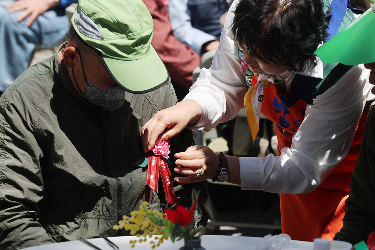 Una voluntaria le coloca un clavel a un se&ntilde;or de la tercera edad durante un evento organizado por la asociaci&oacute;n Dail en el distrito de Dongdaemun-gu, en Se&uacute;l, el 8 de mayo, con motivo del D&iacute;a de los Padres.