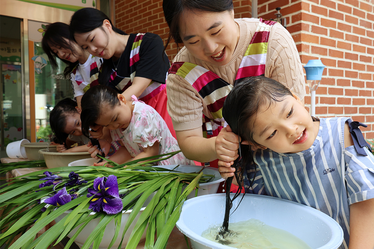 Unos niños reciben un lavado tradicional del cabello, con agua hervida con hojas de cálamo aromático, o 