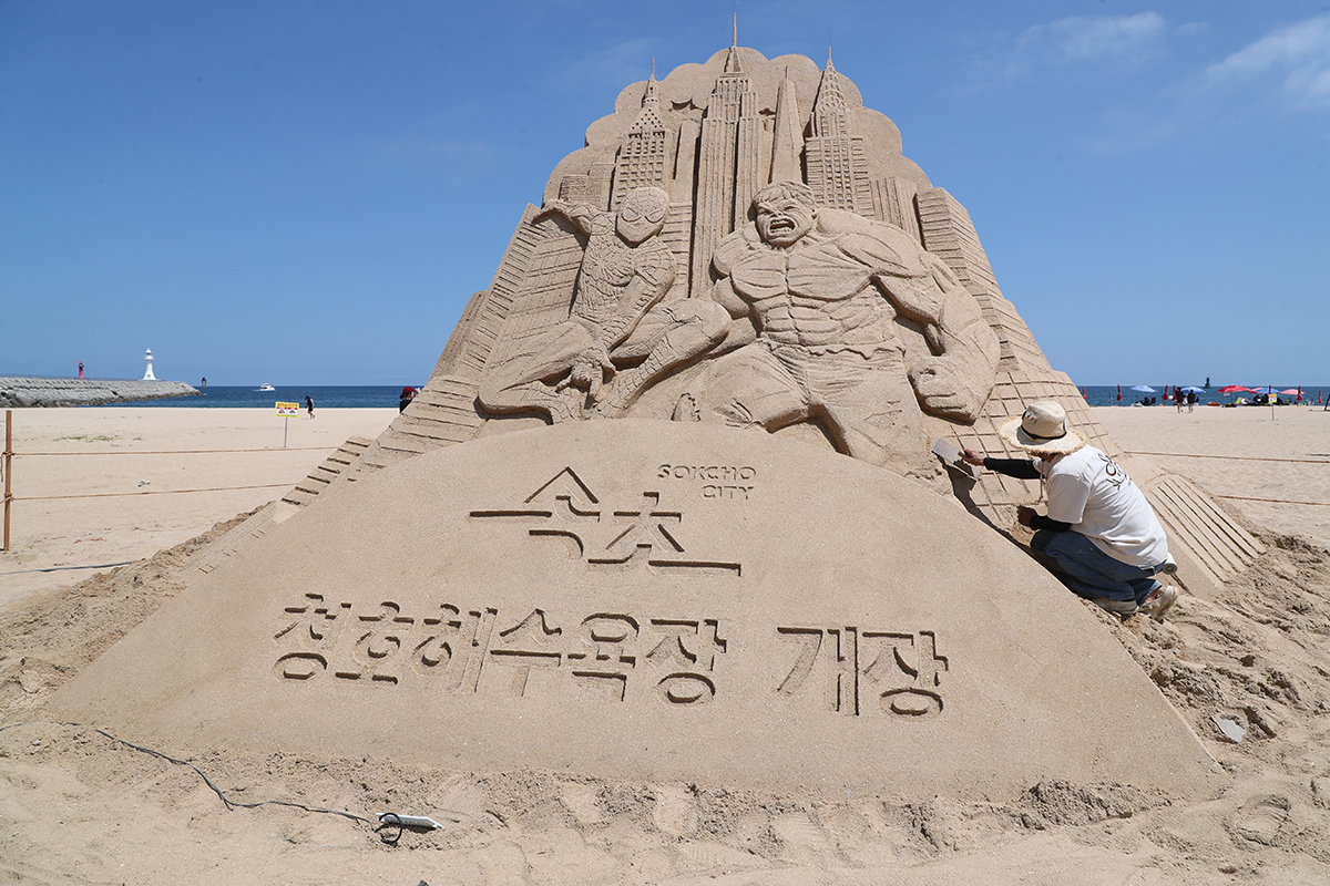 Un escultor crea figuras de arena de Spider-Man y Hulk, el 5 de agosto, en la playa de Cheongho, en la ciudad de Sokcho, en la provincia de Gangwon-do.