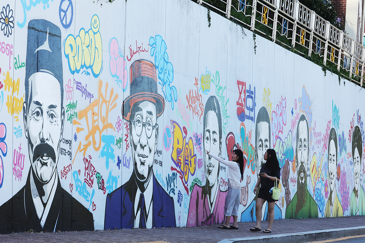El 12 de agosto, en v&iacute;speras de la celebraci&oacute;n del 81&ordm; aniversario de la liberaci&oacute;n nacional, dos transe&uacute;ntes observan los grafitis de los h&eacute;roes de la independencia pintados en la pared de la Escuela Secundaria de Informaci&oacute;n para Ni&ntilde;as Maehyang, en el distrito de Paldal-gu, en la ciudad de Suwon, en la provincia de Gyeonggi-do.